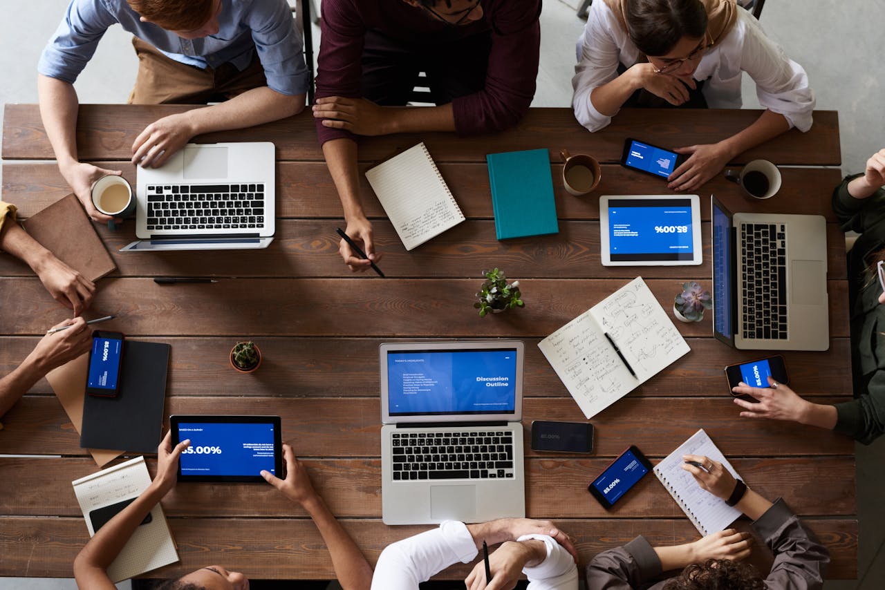gallery-5 Overhead view of a diverse team in a business meeting using laptops and tablets.